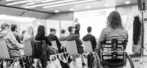 Image showing Rear view of unrecognizable woman on a wheelchair participating at business conference talk.