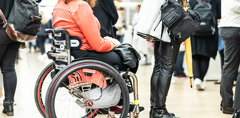 Image showing Close up of unrecognizable hanicapped woman on a wheelchair queuing in line to perform everyday tasks.