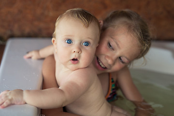 Image showing Two happy little children playing in the bath at the day time.