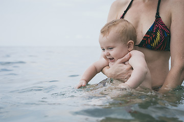 Image showing Mother and baby son playing on the beach at the day time.