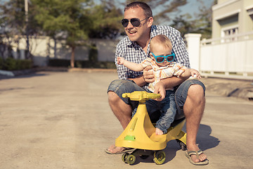 Image showing Father and baby son playing on the road at the day time.