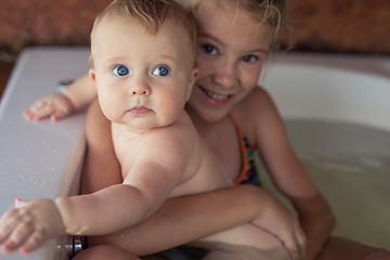 Image showing Two happy little children playing in the bath at the day time.