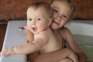 Image showing Two happy little children playing in the bath at the day time.