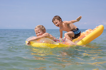 Image showing Two happy little children playing on the beach at the day time.