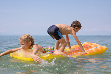 Image showing Two happy little children playing on the beach at the day time.