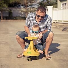 Image showing Father and baby son playing on the road at the day time.