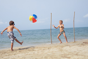 Image showing Two happy little children playing on the beach at the day time.