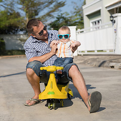 Image showing Father and baby son playing on the road at the day time.