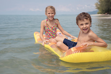 Image showing Two happy little children playing on the beach at the day time.