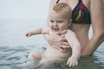 Image showing Mother and baby son playing on the beach at the day time. 