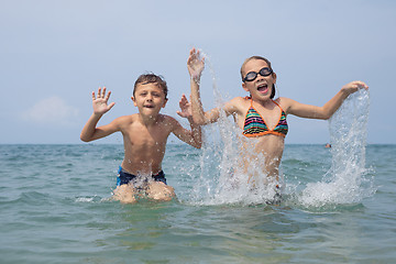 Image showing Two happy little children playing on the beach at the day time.