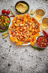 Image showing A plate of delicious tortilla nachos with melted cheese sauce, grilled chicken