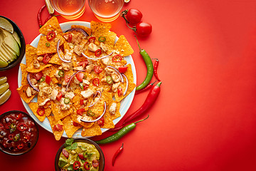 Image showing A plate of delicious tortilla nachos with melted cheese sauce, grilled chicken