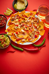 Image showing A plate of delicious tortilla nachos with melted cheese sauce, grilled chicken