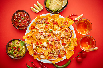 Image showing A plate of delicious tortilla nachos with melted cheese sauce, grilled chicken