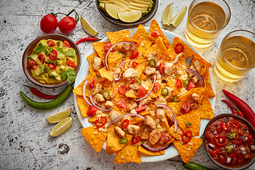 Image showing A plate of delicious tortilla nachos with melted cheese sauce, grilled chicken