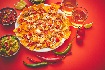 Image showing A plate of delicious tortilla nachos with melted cheese sauce, grilled chicken