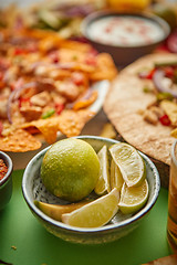 Image showing Close up on lime slices in ceramic bowl with various freshly made Mexican foods