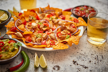 Image showing A plate of delicious tortilla nachos with melted cheese sauce, grilled chicken