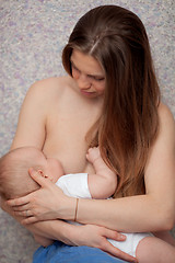 Image showing A long haired young woman breastfeeding a baby