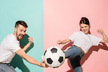 Image showing The young football fans plaing with ball on blue and pink trendy colors.