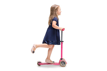 Image showing Smiling cute toddler girl three years riding a scooter over white background