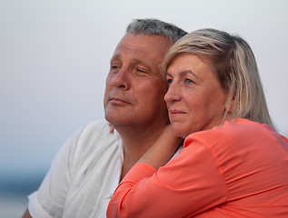 Image showing A middle aged couple sitting close to each other and looking into the distance, smiling