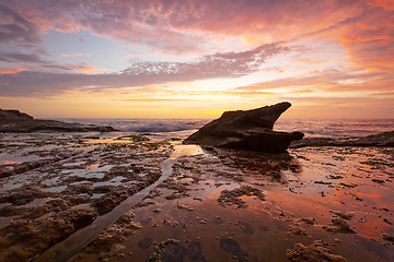 Image showing Sunrise on coastal beach rock shelf with reflections low tide