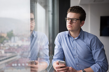 Image showing Businessman Standing In A Modern Building Near The Window With P