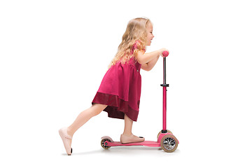 Image showing Smiling cute toddler girl three years riding a scooter over white background