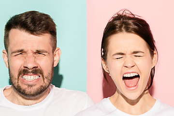 Image showing Closeup portrait of young couple, man, woman. One being excited happy smiling, other serious, concerned, unhappy on pink and blue background. Emotion contrasts