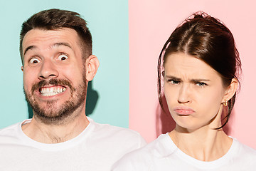 Image showing Closeup portrait of young couple, man, woman. One being excited happy smiling, other serious, concerned, unhappy on pink and blue background. Emotion contrasts