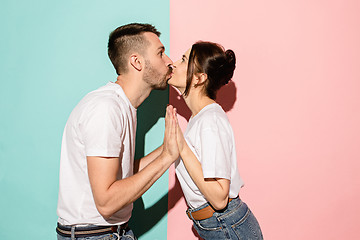 Image showing A view of a loving couple kissing on blue and pink background