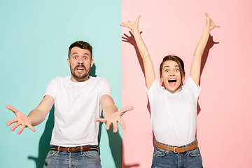 Image showing Closeup portrait of young couple, man, woman. One being excited happy smiling, other serious, concerned, unhappy on pink and blue background. Emotion contrasts