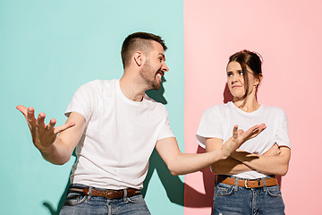 Image showing Closeup portrait of young couple, man, woman. One being excited happy smiling, other serious, concerned, unhappy on pink and blue background. Emotion contrasts