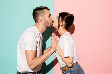 Image showing A view of a loving couple kissing on blue and pink background