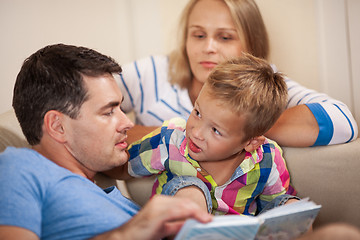 Image showing Curious little boy with mum and dad. Reading book together