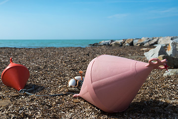 Image showing Two big buoys on the beach, azure sea and the rocky beach