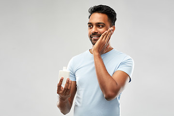 Image showing happy indian man applying lotion to face