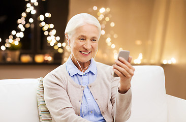 Image showing senior woman with smartphone and earphones on xmas