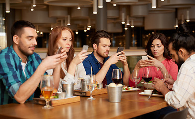 Image showing friends with smartphones at restaurant