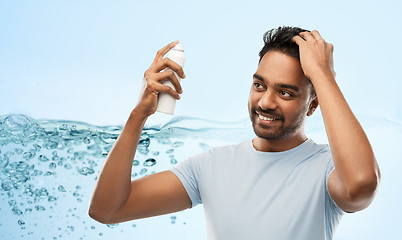 Image showing smiling indian man applying hair spray over gray