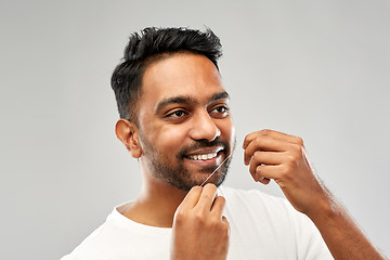 Image showing indian man with dental floss cleaning teeth