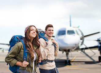 Image showing couple of tourists with backpacks over plane