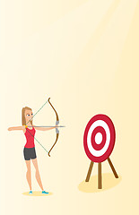 Image showing Sportswoman aiming with a bow and arrow at target.