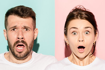 Image showing Closeup portrait of young couple, man, woman. One being excited happy smiling, other serious, concerned, unhappy on pink and blue background. Emotion contrasts