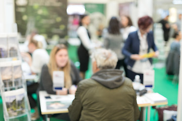 Image showing Blured image of client consulting aobout product with saleswoman at business fair.