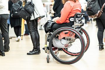 Image showing Close up of unrecognizable hanicapped woman on a wheelchair queuing in line to perform everyday tasks.