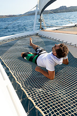 Image showing Sporty man relaxing on a luxury catamaran sailing boat.