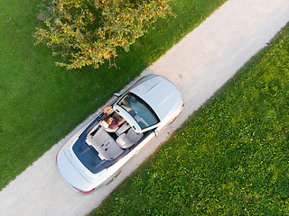 Image showing Aerial view of successful man driving and enjoying his silver convertible luxury sports car on the open country side road